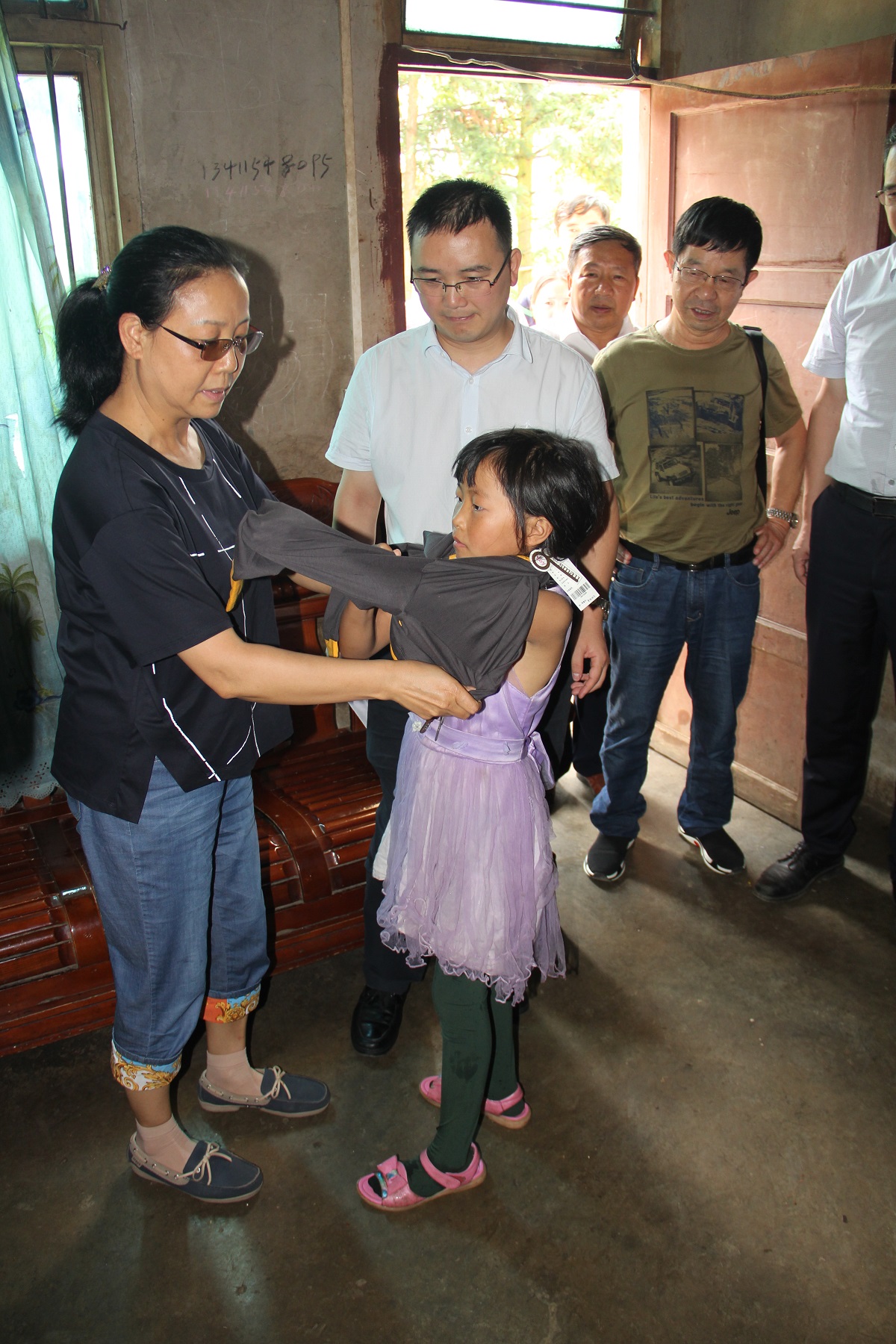 尹秋莲为朱明富小孩穿上省红十字会送去的新衣服.JPG